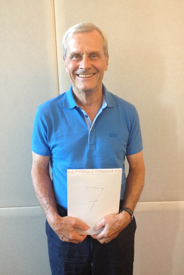 Mathematiker Hanspeter Kraft mit einem Schild mit der Zahl 7 vor dem Bauch. Mathematiker Hanspeter Kraft mit einem Schild mit der Zahl 7 vor dem Bauch.
