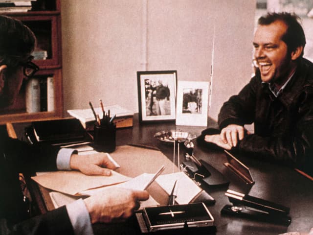 Jack alias McMurphy strahlt den psychologischen Leiter der Irrenanstalt an. Jack alias McMurphy strahlt den psychologischen Leiter der Irrenanstalt an.