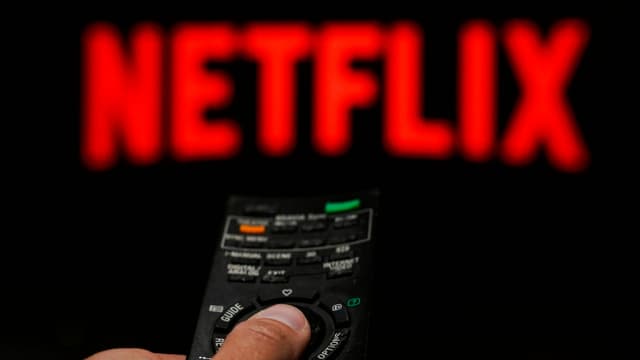 Die Schrift "NETFLIX" auf dem Fernseher, mit einer Fernbedienung im Vordergrund. Die Schrift "NETFLIX" auf dem Fernseher, mit einer Fernbedienung im Vordergrund.
