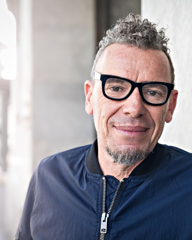 Autor Tom Kummer mit schwarz umrandeter Brille und dunkler Bomberjacke. Autor Tom Kummer mit schwarz umrandeter Brille und dunkler Bomberjacke.