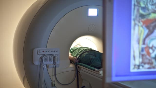 Ein Mann in einem MRI, vorne der Rand eines Bildschirms. Ein Mann in einem MRI, vorne der Rand eines Bildschirms.
