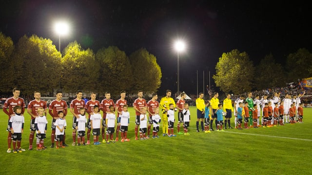 Die beiden Mannschaften vor dem Anpfiff - am Spielfeldrand grosse Bäume. Die beiden Mannschaften vor dem Anpfiff - am Spielfeldrand grosse Bäume.