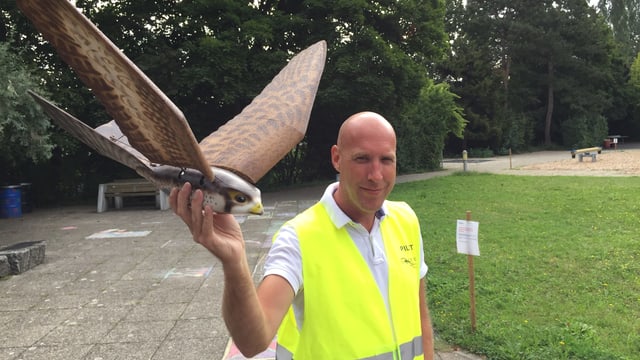 Mann mit gelber Weste und Vogel-Drohne in der Hand. Mann mit gelber Weste und Vogel-Drohne in der Hand.