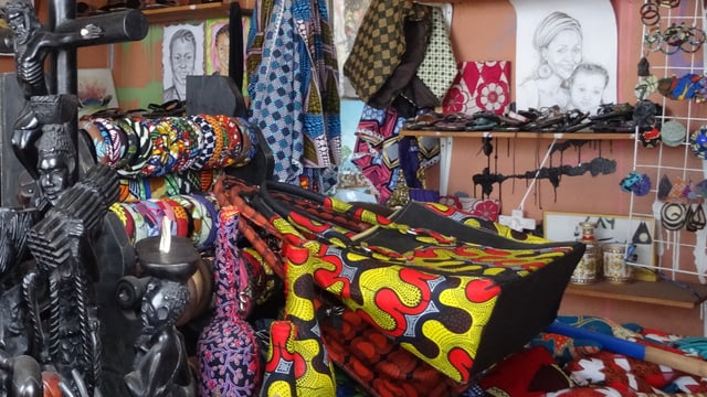 Geschnitzte Figuren, bunte Taschen und Tücher, Armreifen und Zeichnungen in Mapendos Boutique Geschnitzte Figuren, bunte Taschen und Tücher, Armreifen und Zeichnungen in Mapendos Boutique