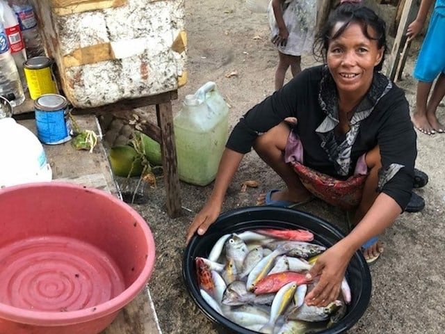 Eine Frau vor einem Kübel mit Fischen. Eine Frau vor einem Kübel mit Fischen.