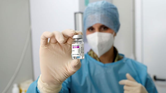 Ärztin in Montur hält Fläschchen mit Impfstoff in die Kamera. Ärztin in Montur hält Fläschchen mit Impfstoff in die Kamera.