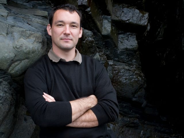 Cynan Jones steht vor einer Steinmauer. Cynan Jones steht vor einer Steinmauer.