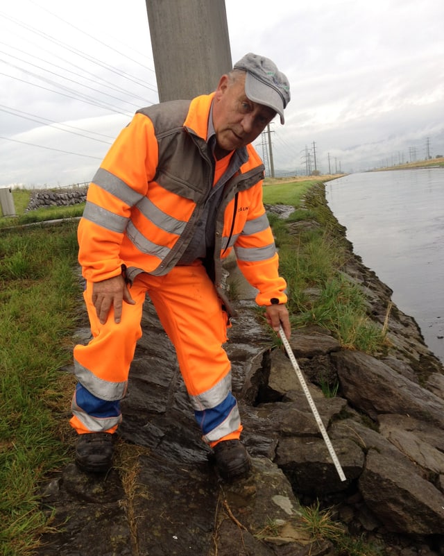 Mann in orangem Anzug neben Linthkanal. Mann in orangem Anzug neben Linthkanal.