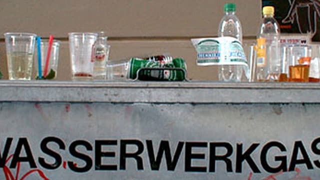 Abfallcontaier mit der Aufschrift Wassergasse. Darauf stehen leere Petflaschen und Bierdosen und -bescher. Abfallcontaier mit der Aufschrift Wassergasse. Darauf stehen leere Petflaschen und Bierdosen und -bescher.