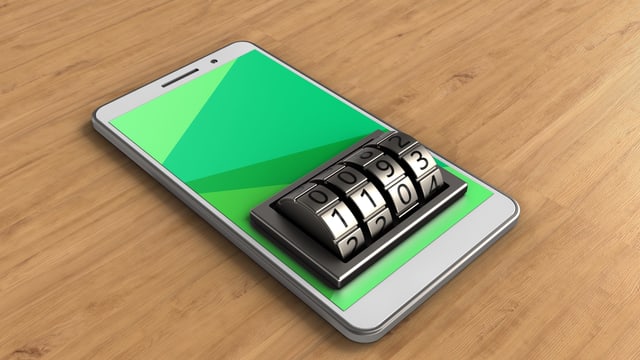 Ein Smartphone liegt auf einem Tisch. Wo man den Pin eintippt, ist ein Zahlenschloss montiert. Ein Smartphone liegt auf einem Tisch. Wo man den Pin eintippt, ist ein Zahlenschloss montiert.