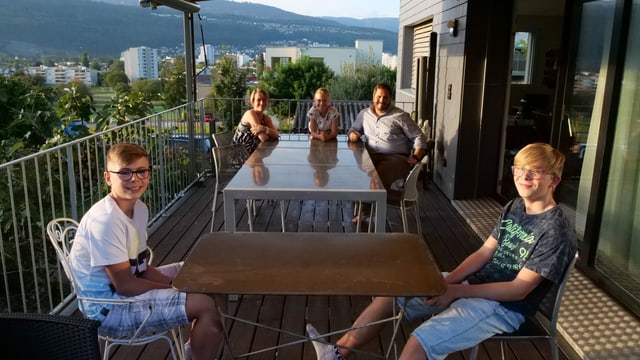 Alle sitzen auf der Terrasse. Die Buben an einem separaten Tisch. Alle sitzen auf der Terrasse. Die Buben an einem separaten Tisch.