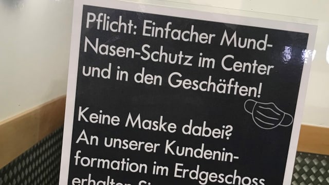 Tafel mit der Aufschrift: Maskenpflicht im Einkaufszentrum Lago. Tafel mit der Aufschrift: Maskenpflicht im Einkaufszentrum Lago.