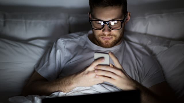 Ein Mann im Bed am Handy Ein Mann im Bed am Handy