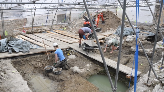 Drei Leute arbeiten in einer Ausgrabungsstätte. Knien auf dem Boden und buddeln mit den Händen in der Erde. Drei Leute arbeiten in einer Ausgrabungsstätte. Knien auf dem Boden und buddeln mit den Händen in der Erde.