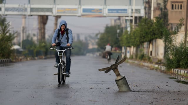 Fahrradfahrer neben einer Streubombe Fahrradfahrer neben einer Streubombe