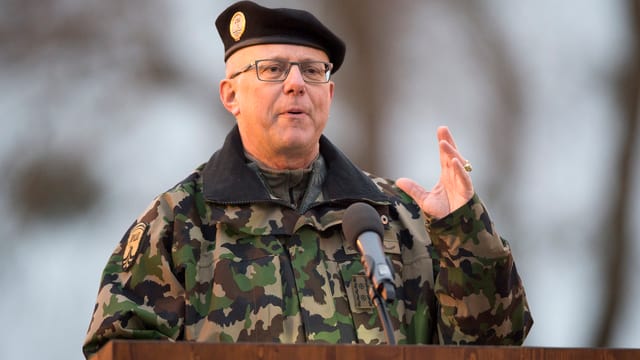 Mann in Tarnuniform an einem Rednerpult, er hat die linke Hand erhoben. Mann in Tarnuniform an einem Rednerpult, er hat die linke Hand erhoben.