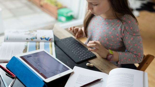 Ein Mädchen macht Hausaufgaben an einem Tablet. Ein Mädchen macht Hausaufgaben an einem Tablet.