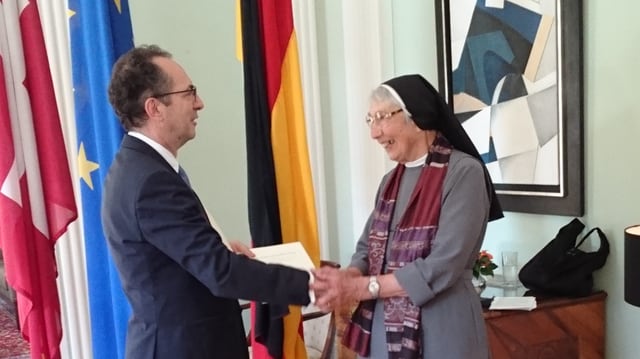 Eine Mann übergibt einer Nonne einen Orden. Eine Mann übergibt einer Nonne einen Orden.