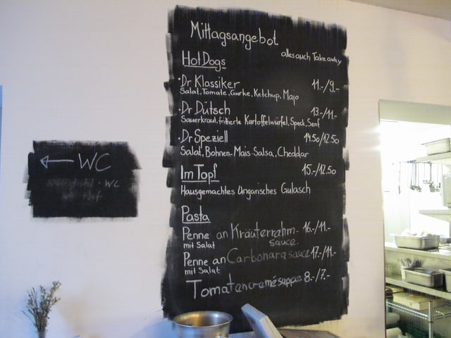 Hot-Dogs, Teigwaren und Suppe - das Mittagsangebot auf dem Menu an der Wand im «Provisorium 46» Hot-Dogs, Teigwaren und Suppe - das Mittagsangebot auf dem Menu an der Wand im «Provisorium 46»