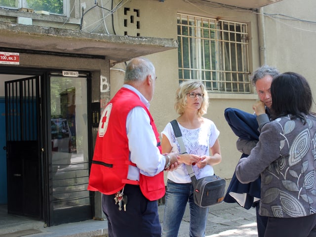 Mitarbeiter des Bulgarischen Roten Kreuzes diskutieren vor dem Hauseingang.