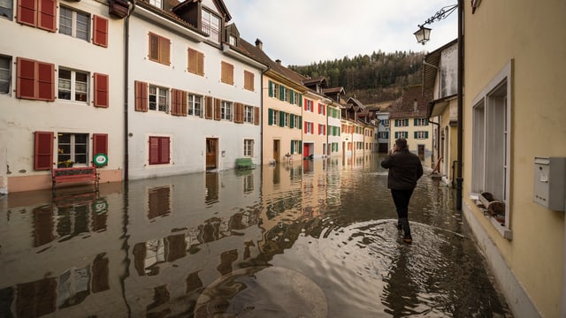 Mann watet durch das Wasser. Regenfälle haben die Strassen überschwemmt. Mann watet durch das Wasser. Regenfälle haben die Strassen überschwemmt.