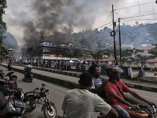 Demonstranten in West Papua und ein brennendes Haus Demonstranten in West Papua und ein brennendes Haus