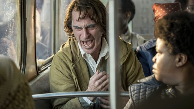 Ein älterer Mann sitzt in einer U-Bahn und lacht krampfhaft. Ein älterer Mann sitzt in einer U-Bahn und lacht krampfhaft.