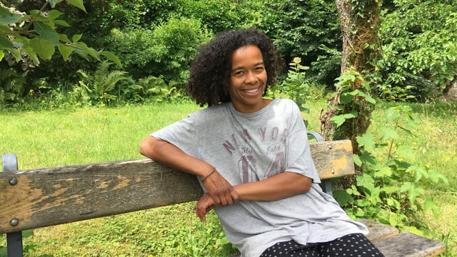Myriam Diarra sitzt auf einer Parkbank. Myriam Diarra sitzt auf einer Parkbank.