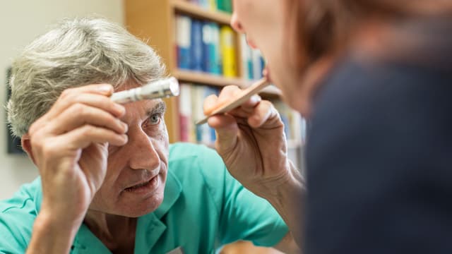 Arzt leuchtet einer Patientin in den Mund. Arzt leuchtet einer Patientin in den Mund.