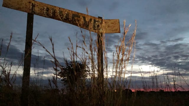 Ein rostiges Schild auf einer Wiese in der Morgendämmerung. Ein rostiges Schild auf einer Wiese in der Morgendämmerung.