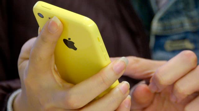 Frauenhände in Grossaufnahme halten ein gelbes iPhone Frauenhände in Grossaufnahme halten ein gelbes iPhone