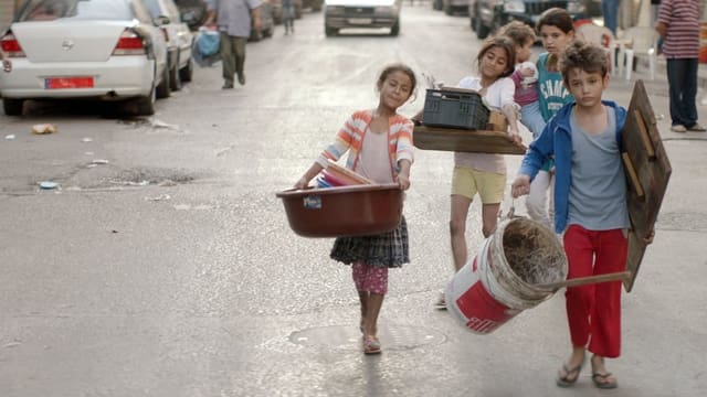 Vier Kinder tragen Baumaterial durch eine Strasse. Vier Kinder tragen Baumaterial durch eine Strasse.