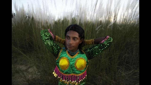 Ein junger Mann in bunt glitzerndem Kleid vor einer Wiese Ein junger Mann in bunt glitzerndem Kleid vor einer Wiese