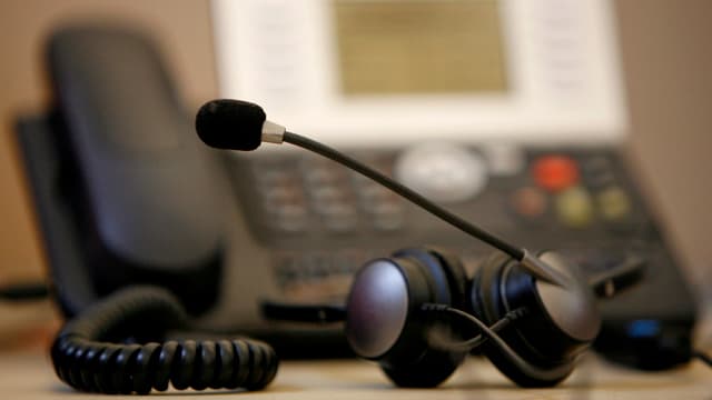 Ein Headset liegt vor einem Telefon. Ein Headset liegt vor einem Telefon.