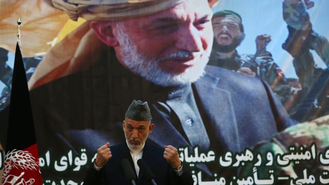 Präsident Hamid Karzai bei seiner Rede zur Übernahme der Sicherheitsverantwortung in Afghanistan. Im Hintergrund ein grosses Bild eines solzen afghanischen Mannes mit Turban. Präsident Hamid Karzai bei seiner Rede zur Übernahme der Sicherheitsverantwortung in Afghanistan. Im Hintergrund ein grosses Bild eines solzen afghanischen Mannes mit Turban.