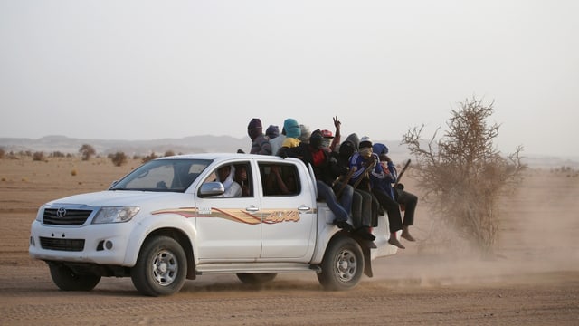 Pickup in der Wüste vollbeladen mit jungen Männern.