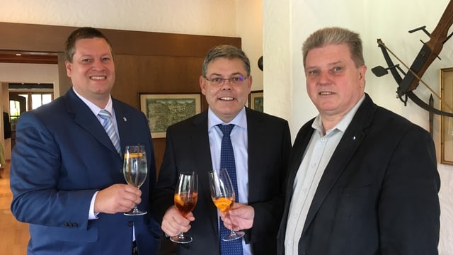 Drei Männer im Anzug stossen an. Drei Männer im Anzug stossen an.