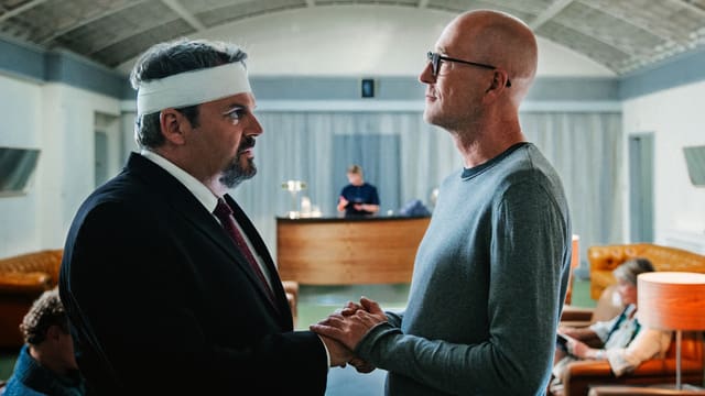 Professor Mankovsky hält die Hand von Luc Conrad. Er ist am Kopf verletzt und trägt einen Verband um den Kopf. Professor Mankovsky hält die Hand von Luc Conrad. Er ist am Kopf verletzt und trägt einen Verband um den Kopf.