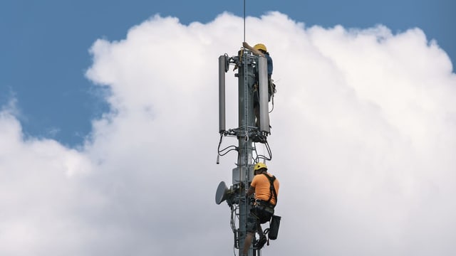 Menschen montieren eine Mobilfunk-Antenne Menschen montieren eine Mobilfunk-Antenne