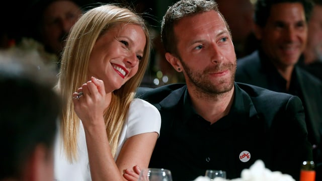Gwyneth Paltrow und Chris Martin sitzen verliebt nebeneinander. Er trägt einen schwarzen Anzug, sie ein weisses Kleid. Gwyneth Paltrow und Chris Martin sitzen verliebt nebeneinander. Er trägt einen schwarzen Anzug, sie ein weisses Kleid.