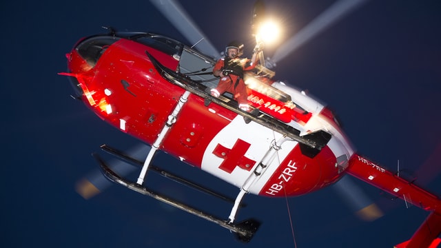 Ein Helikopter der Rega fliegt vor dem Nachthimmel Ein Helikopter der Rega fliegt vor dem Nachthimmel
