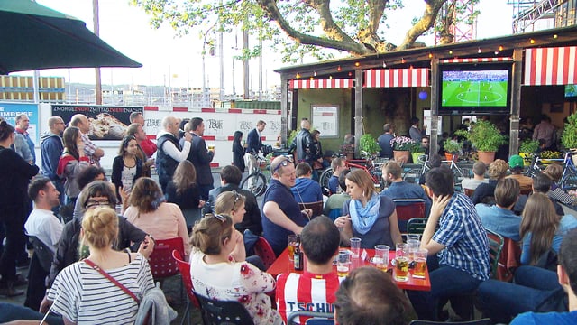 Besucherinnen und Besucher in der Fussball-Beiz Piccolo Giardino mit Fernseher im Hintergrund Besucherinnen und Besucher in der Fussball-Beiz Piccolo Giardino mit Fernseher im Hintergrund