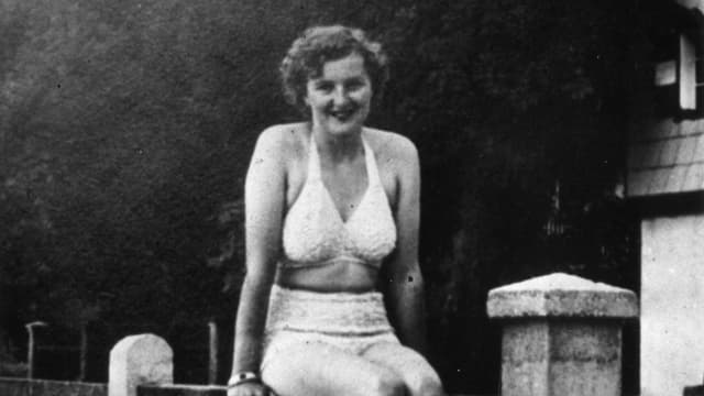Junge Frau sitzt auf einem Zaun, altes Foto. Junge Frau sitzt auf einem Zaun, altes Foto.