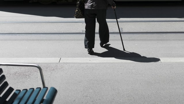 Ältere Frau mit Gehstock überquert Strasse Ältere Frau mit Gehstock überquert Strasse