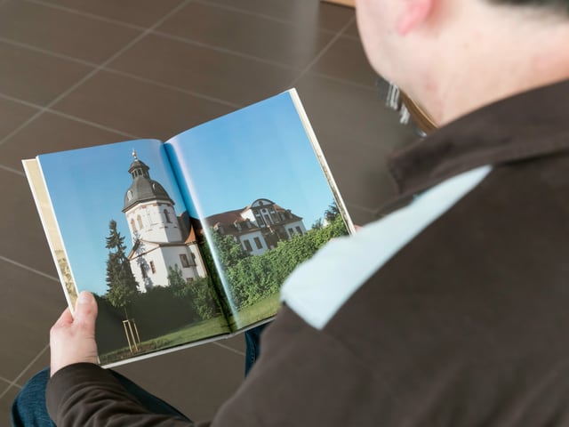 Ein Mann betrachtet ein Buch mit Bildern aus Thüringen. Ein Mann betrachtet ein Buch mit Bildern aus Thüringen.