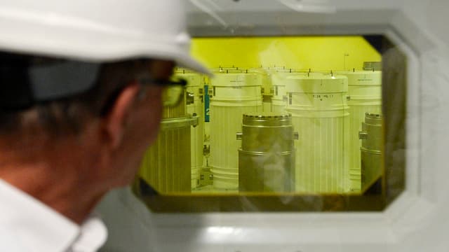 Ein Mann schaut durch ein Fenster in einen Raum mit Fässern und gelbem Licht Ein Mann schaut durch ein Fenster in einen Raum mit Fässern und gelbem Licht