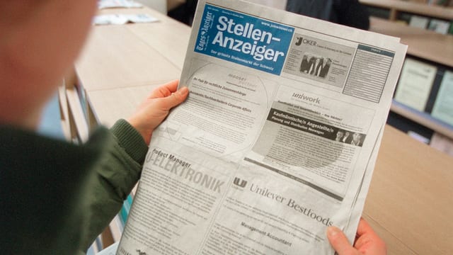 Ein Stellensuchender liest den Stellenanzeiger Ein Stellensuchender liest den Stellenanzeiger
