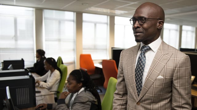Ein Afrikaner in einem Anzug mit Krawatte in einem Büro. Ein Afrikaner in einem Anzug mit Krawatte in einem Büro.