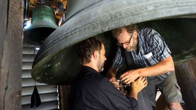 Peter Conradin Zumthor und Gabriel Schneider umwickeln den Klöppel einer Glocke mit Teilen eines Motorradpneus. Peter Conradin Zumthor und Gabriel Schneider umwickeln den Klöppel einer Glocke mit Teilen eines Motorradpneus.
