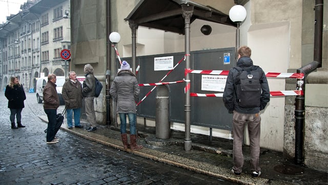 Mehrer Menschen schauen auf die abgesperrten Toiletten. Mehrer Menschen schauen auf die abgesperrten Toiletten.